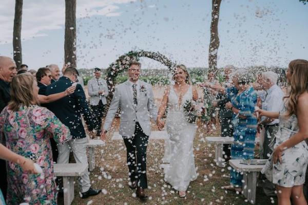 Guests throw co<em></em>nfetti over the newlyweds.